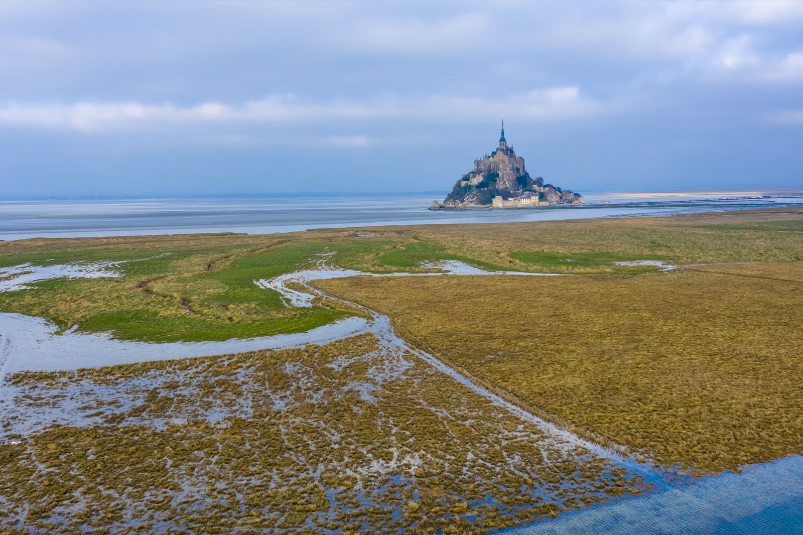Kwelders en getijdengeulen aan de rand van de baai, met Mont-Saint-Michel aan de horizon